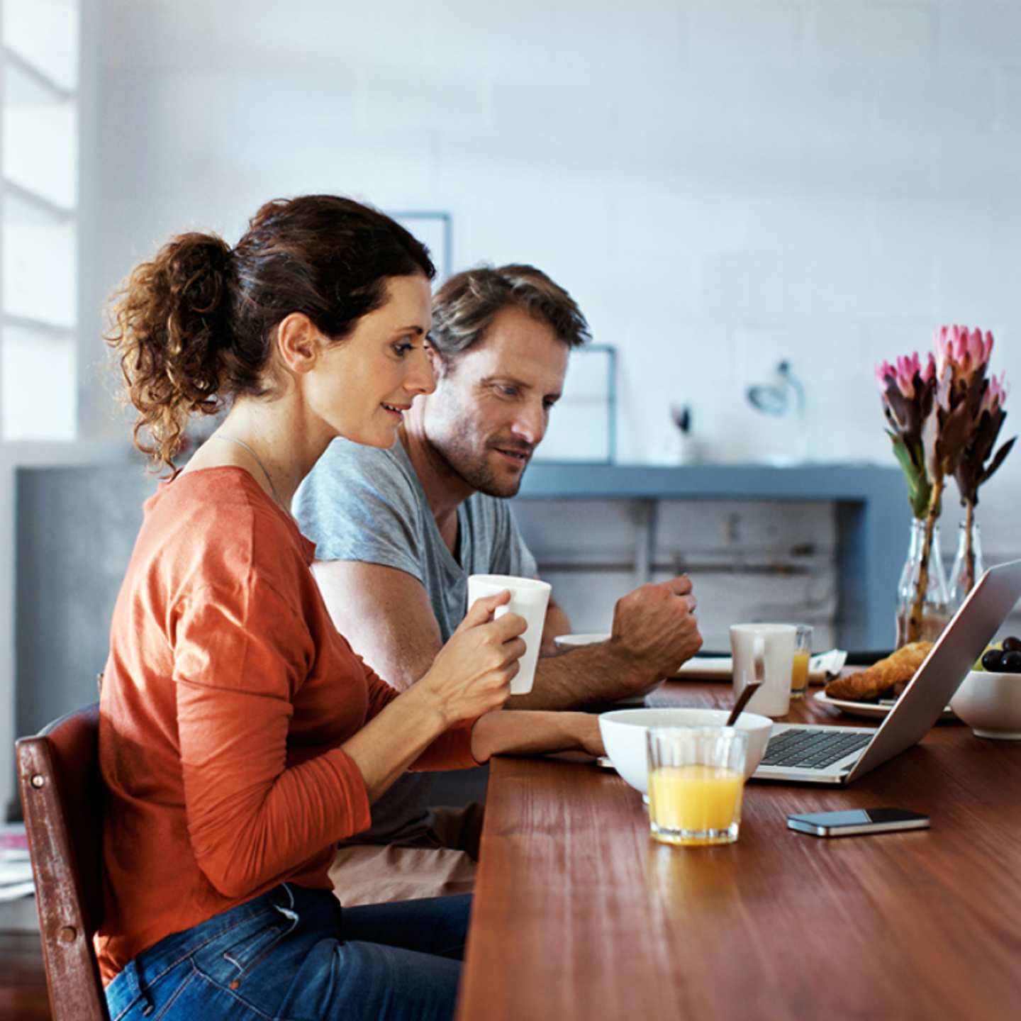 Couple working on laptop at kitchen table. 