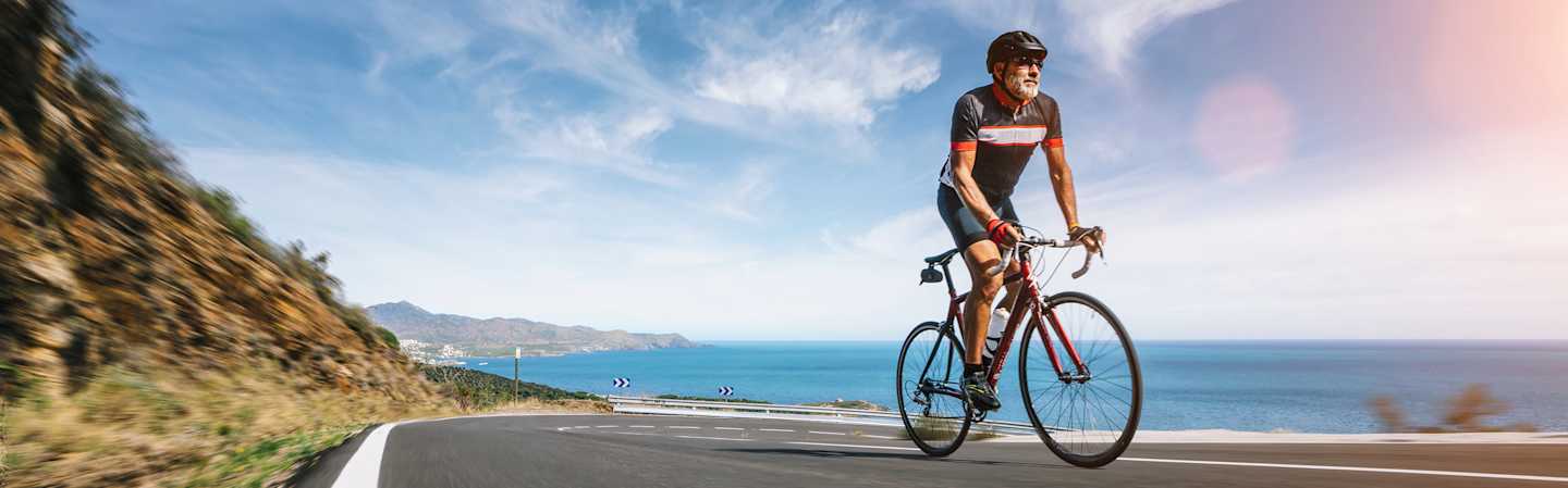 Retired man riding bike along coast.