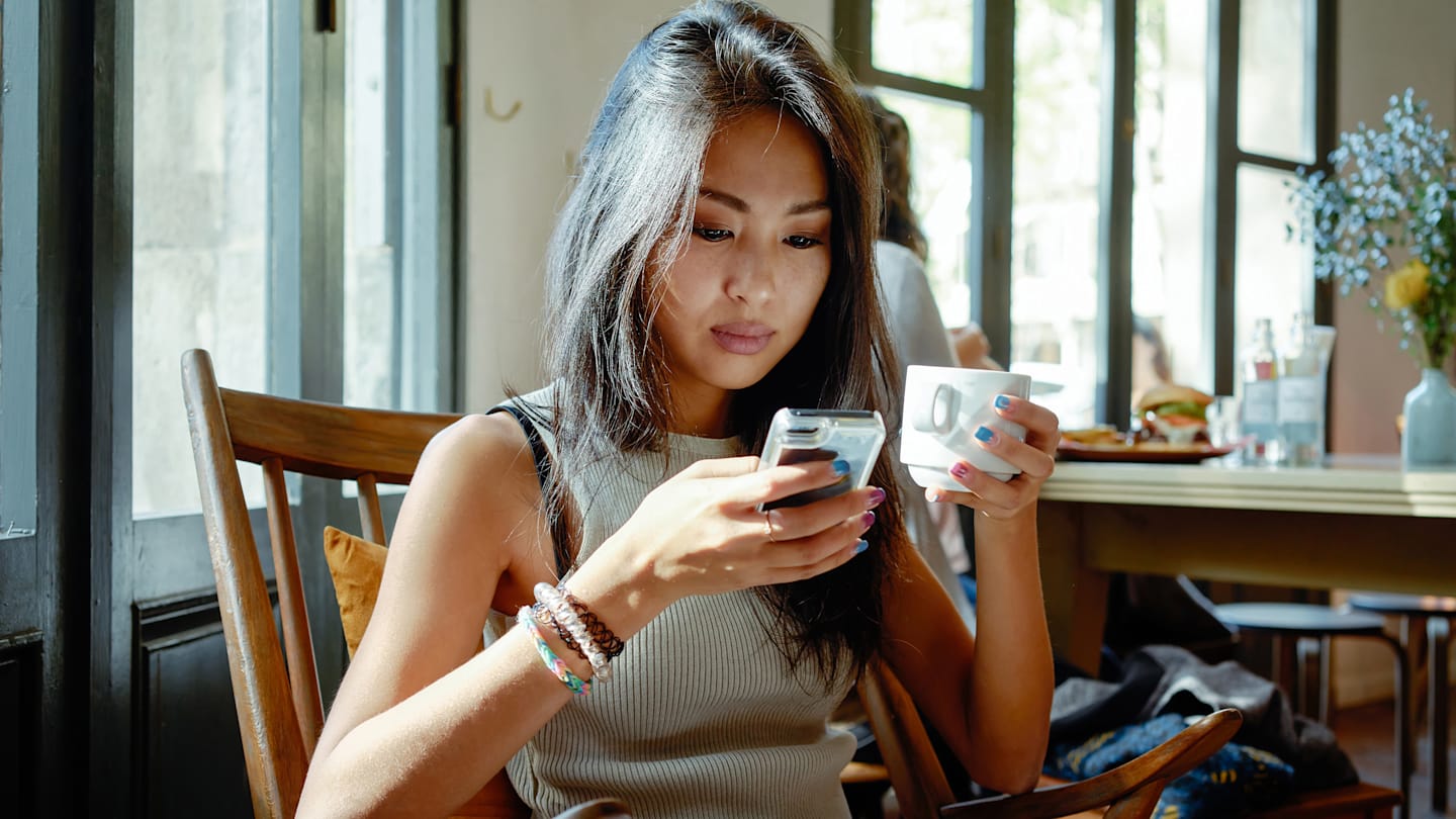 Woman in coffee shop looking at phone.