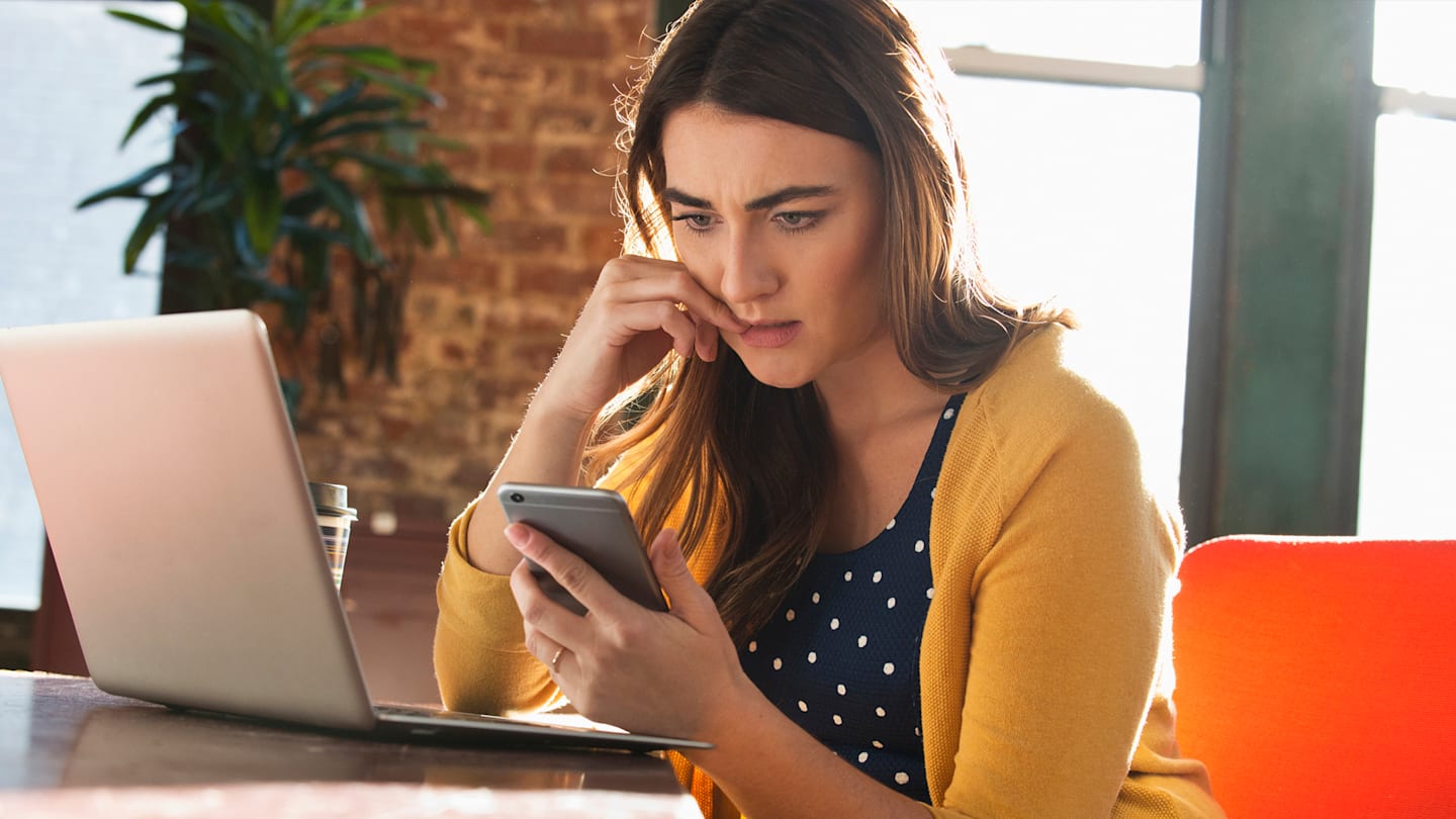 Woman looking stressed while holding phone.