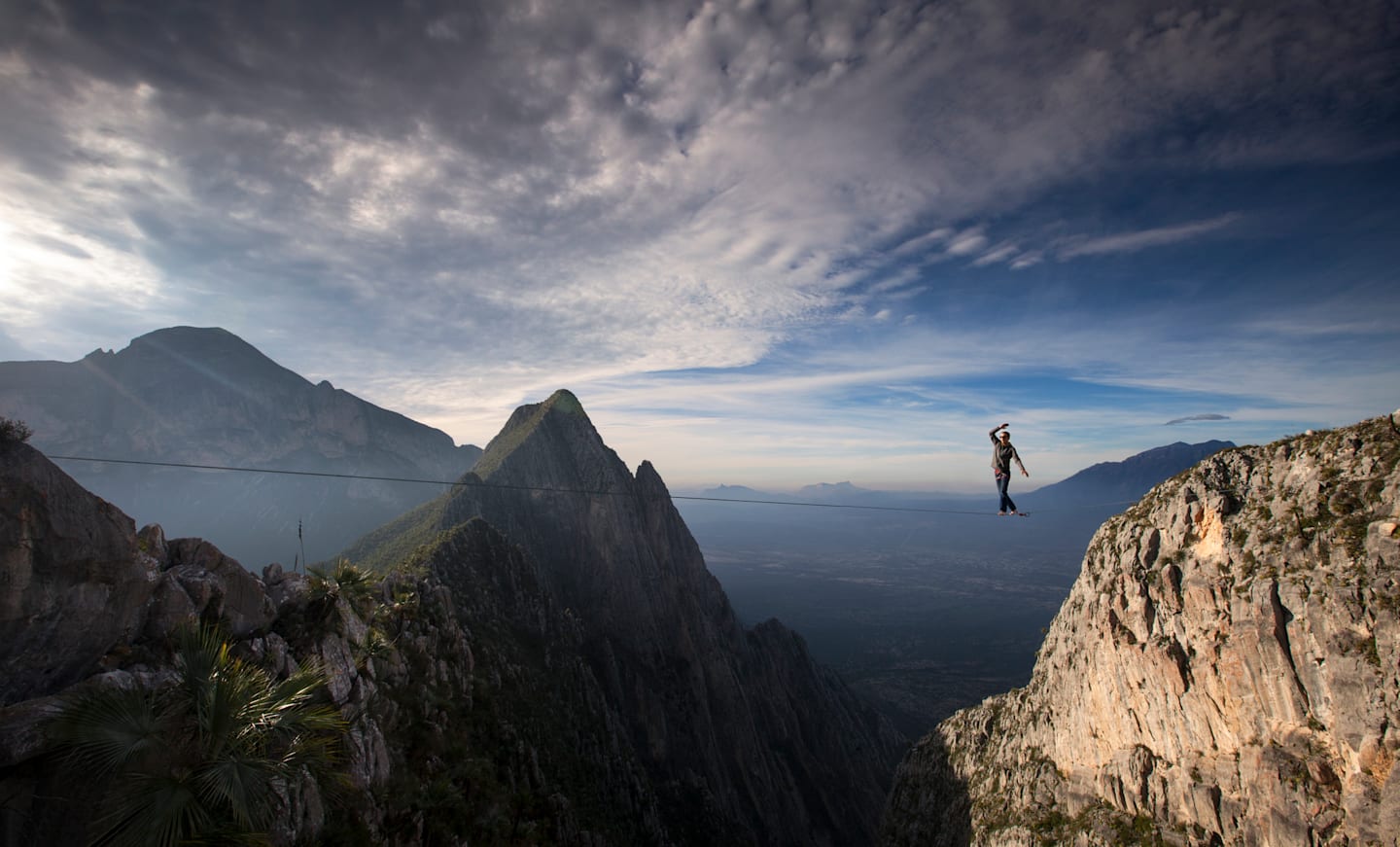 Person balancing on rope in outdoor environment.