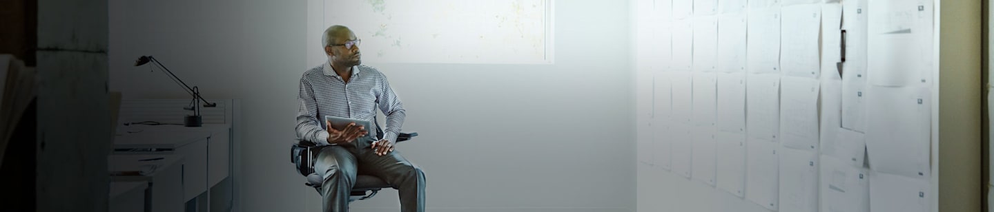 A man looking at papers tacked onto the wall.