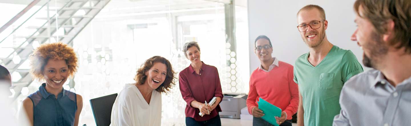 Co-workers laughing during after-meeting discussion.