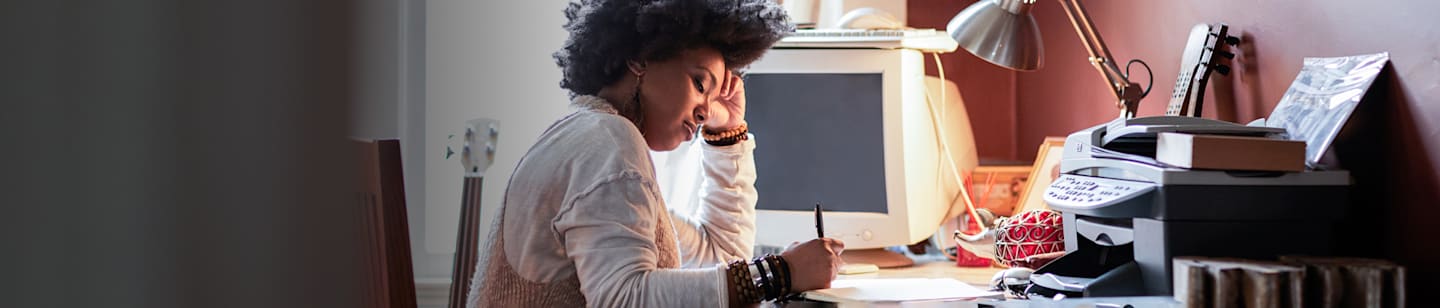 A woman sitting at her desk writing on a piece of paper.