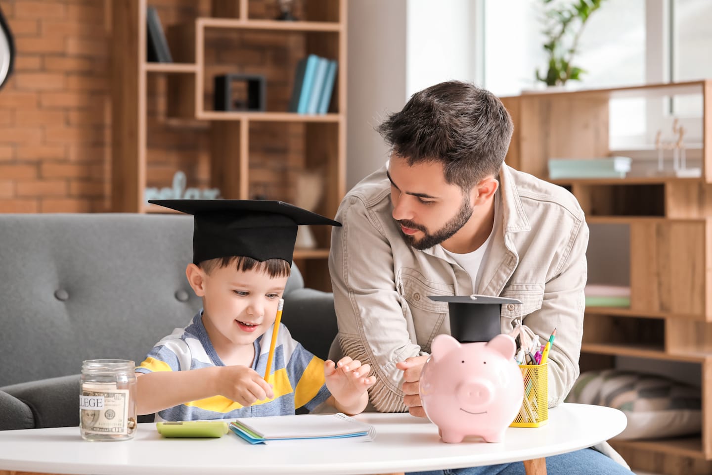 Father playing with son while son wears graduation cap.