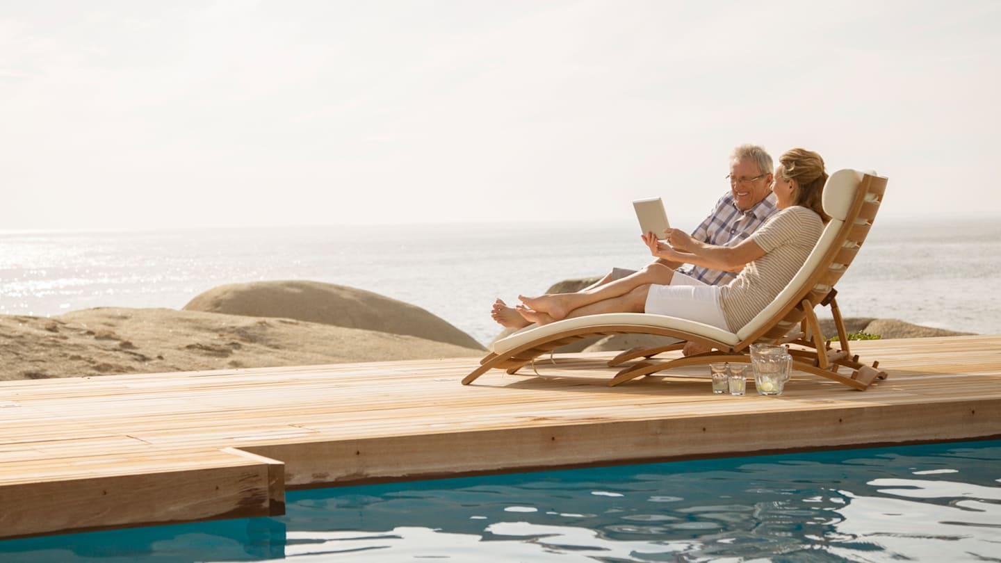 Retired couple lounging on ocean dock.