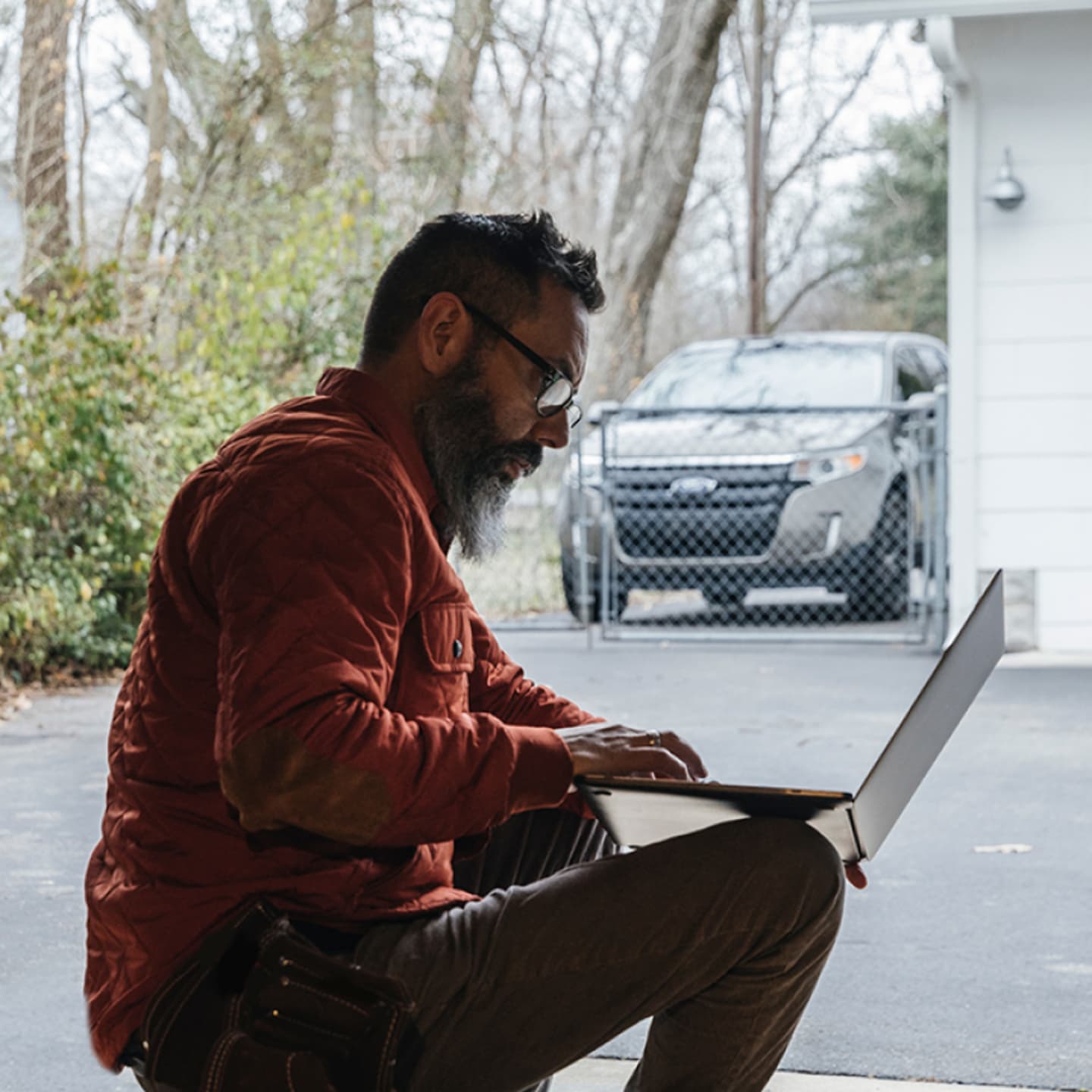 Man on laptop outside of home.