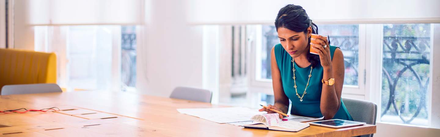 Woman looking over papers at kitchen table.