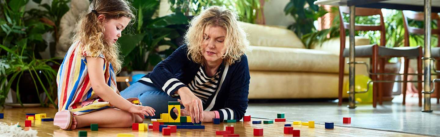 Grandmother playing with grandchild on living room floor.