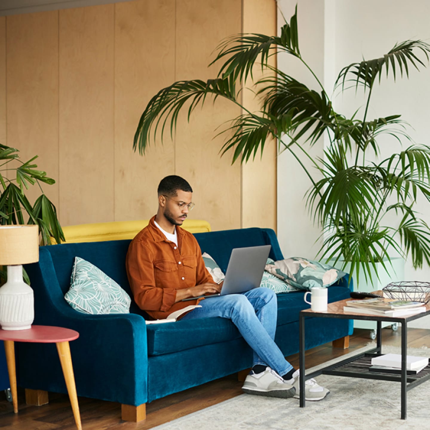 Man sitting on couch with laptop in living room.