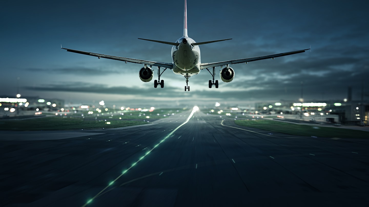 Airplane landing on runway at night.
