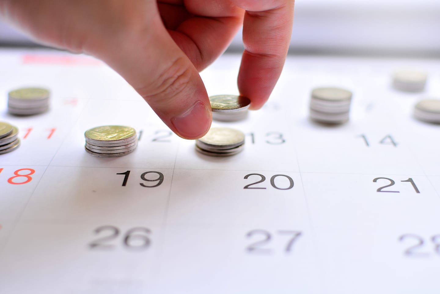 Hand placing coins on calendar. 
