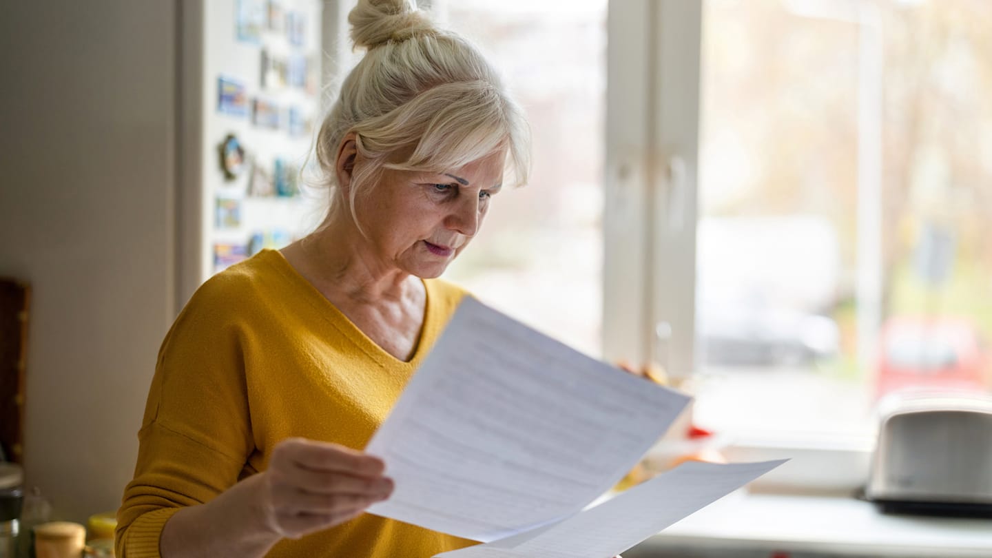 A woman reviews paperwork and considers updates to her finances.