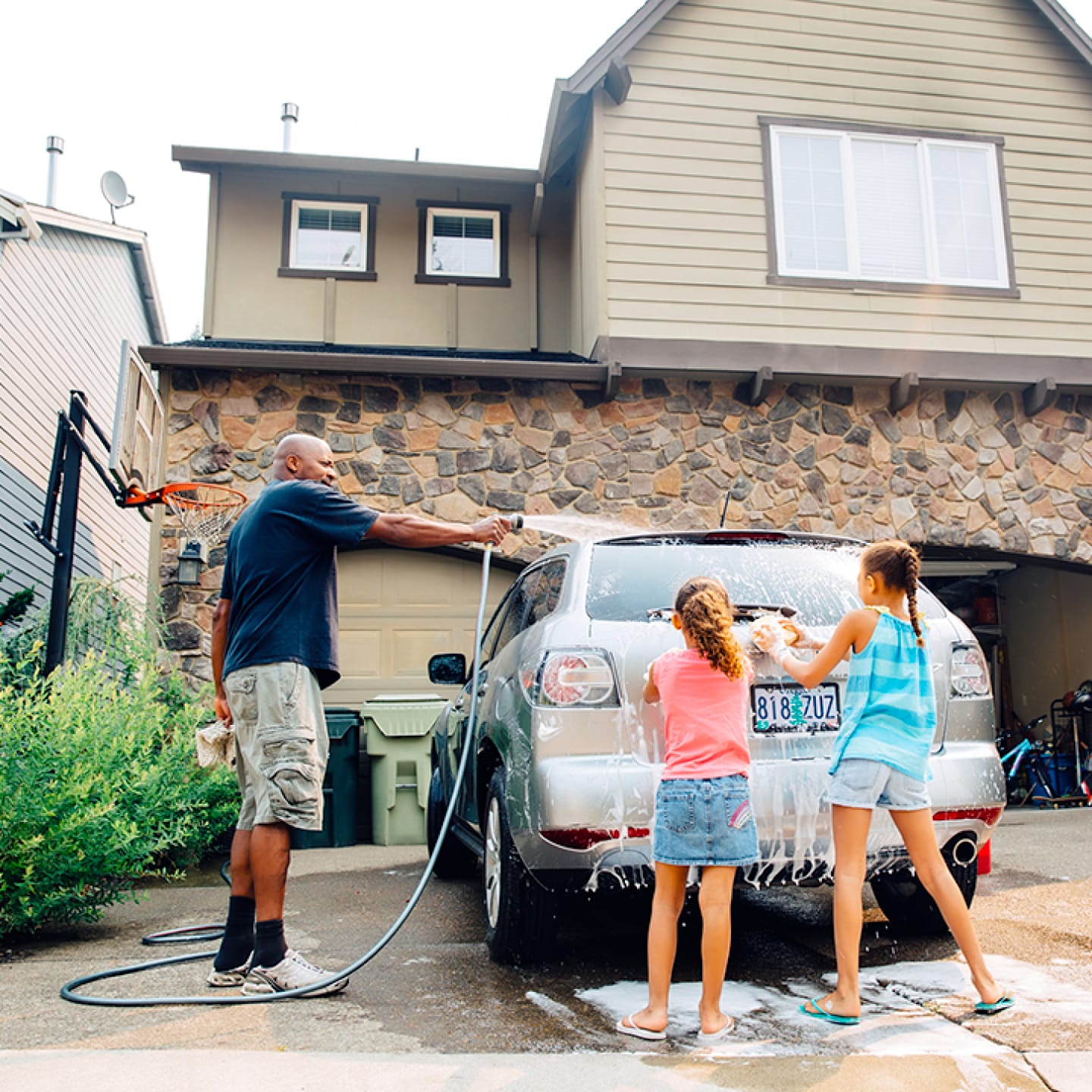 Family washing car in home driveway.