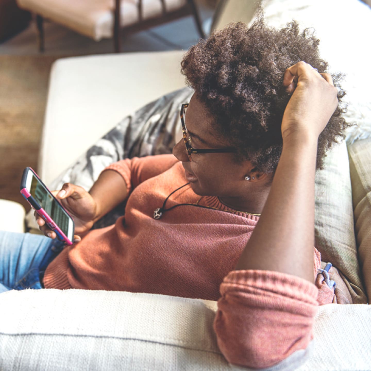 Woman reclining on sofa with phone.