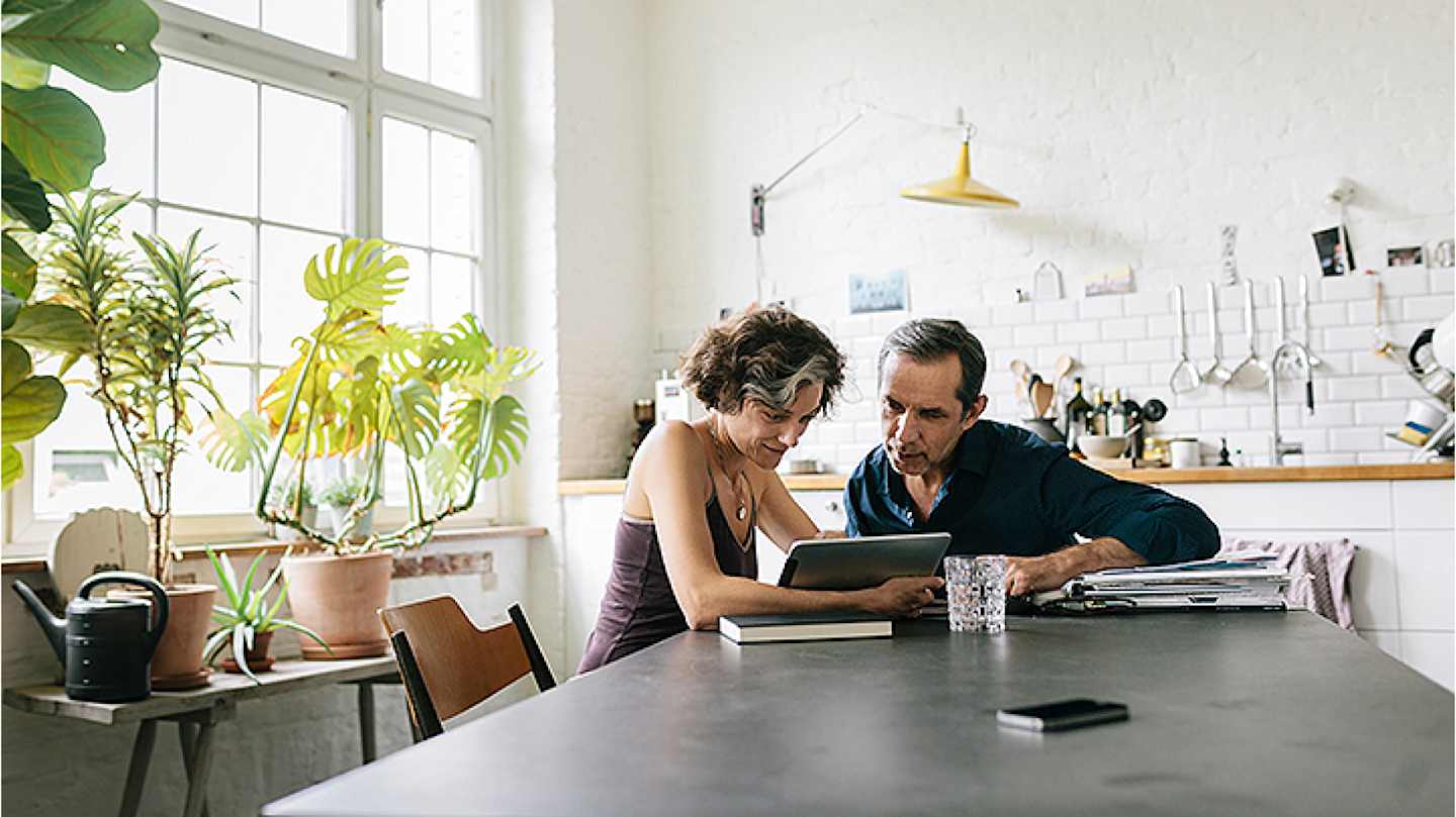 Older couple looking at tablet in kitchen.