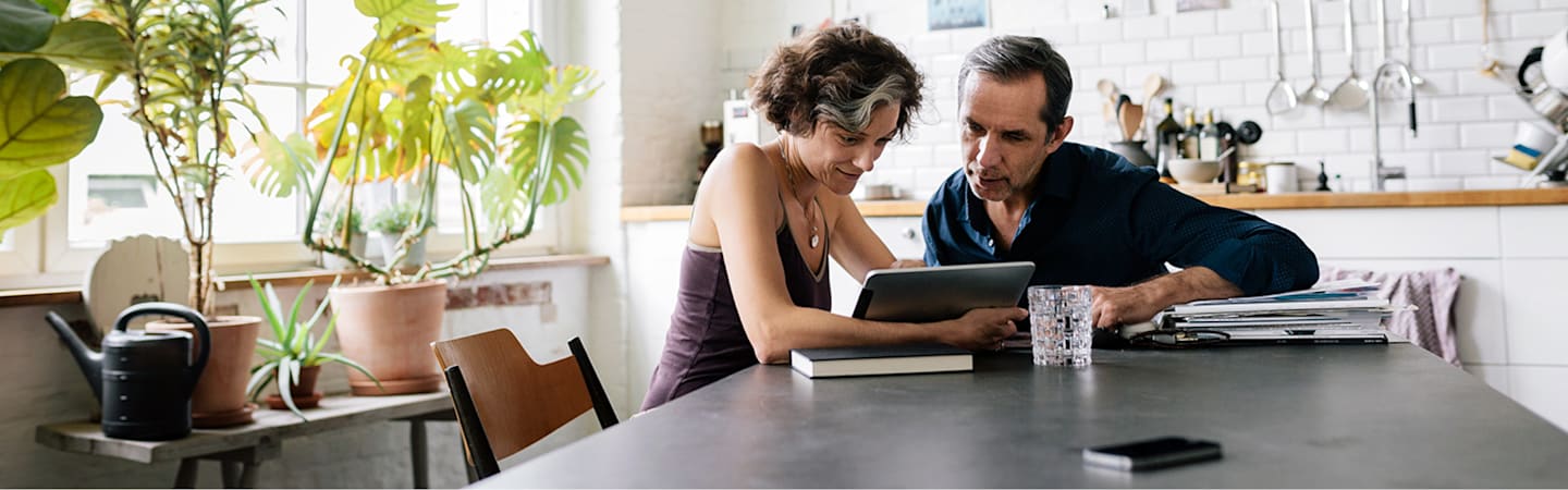 Older couple looking at tablet in kitchen.