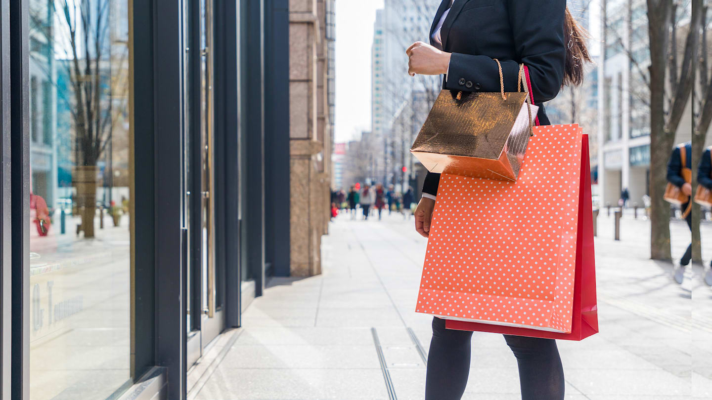 Woman holding expensive shopping bags in front of a store.