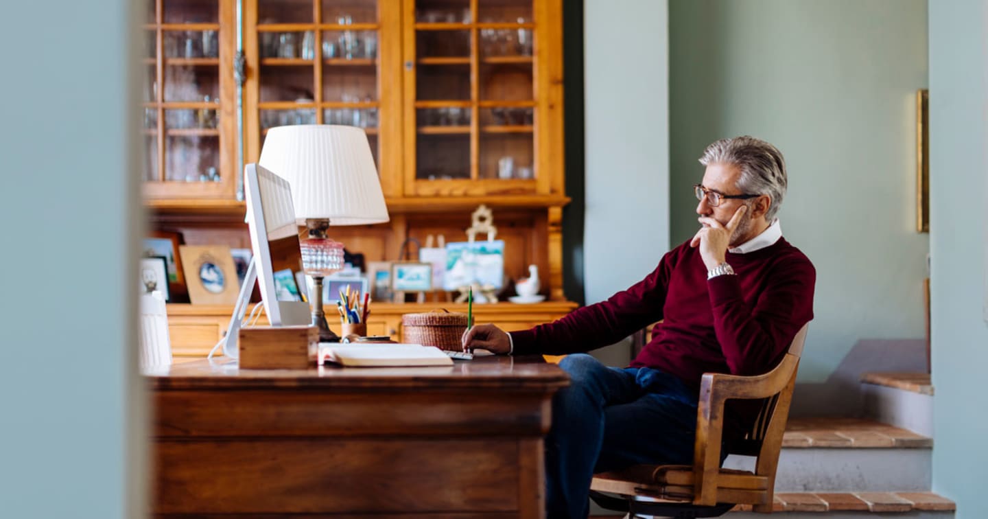 An older man sitting at his desk.