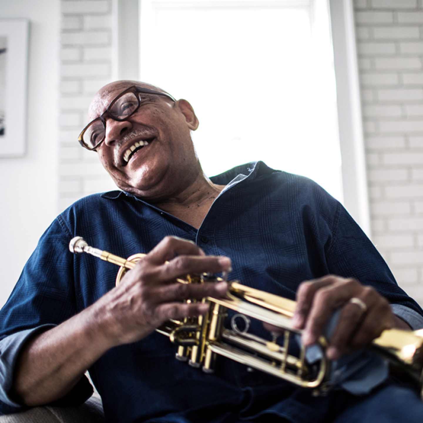 Older man smiling with trumpet.