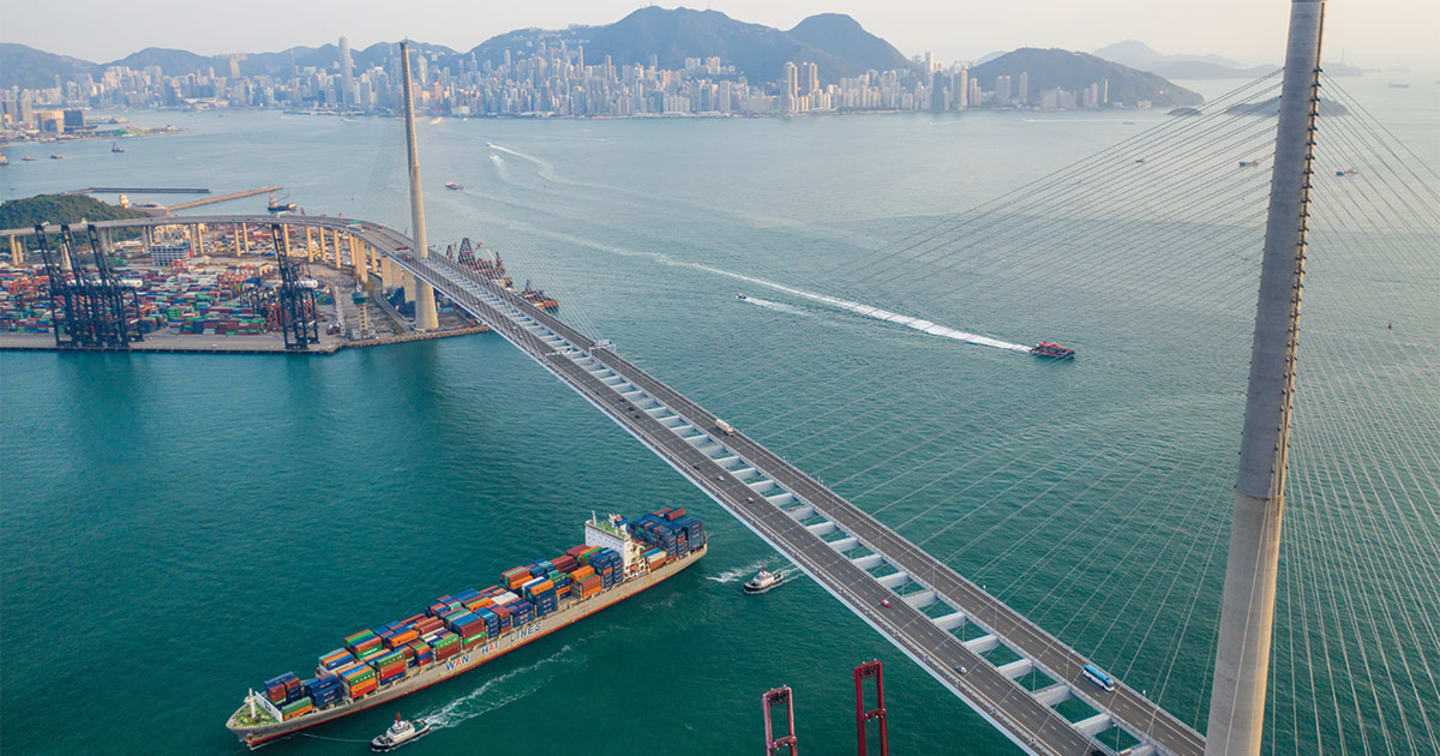 A cargo ship sailing under a bridge.