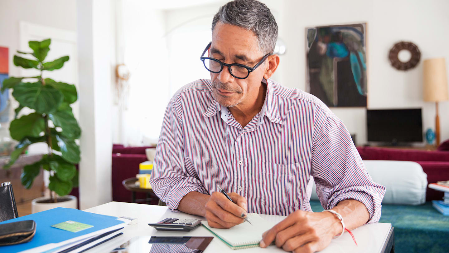 Older man looking over paperwork at home.