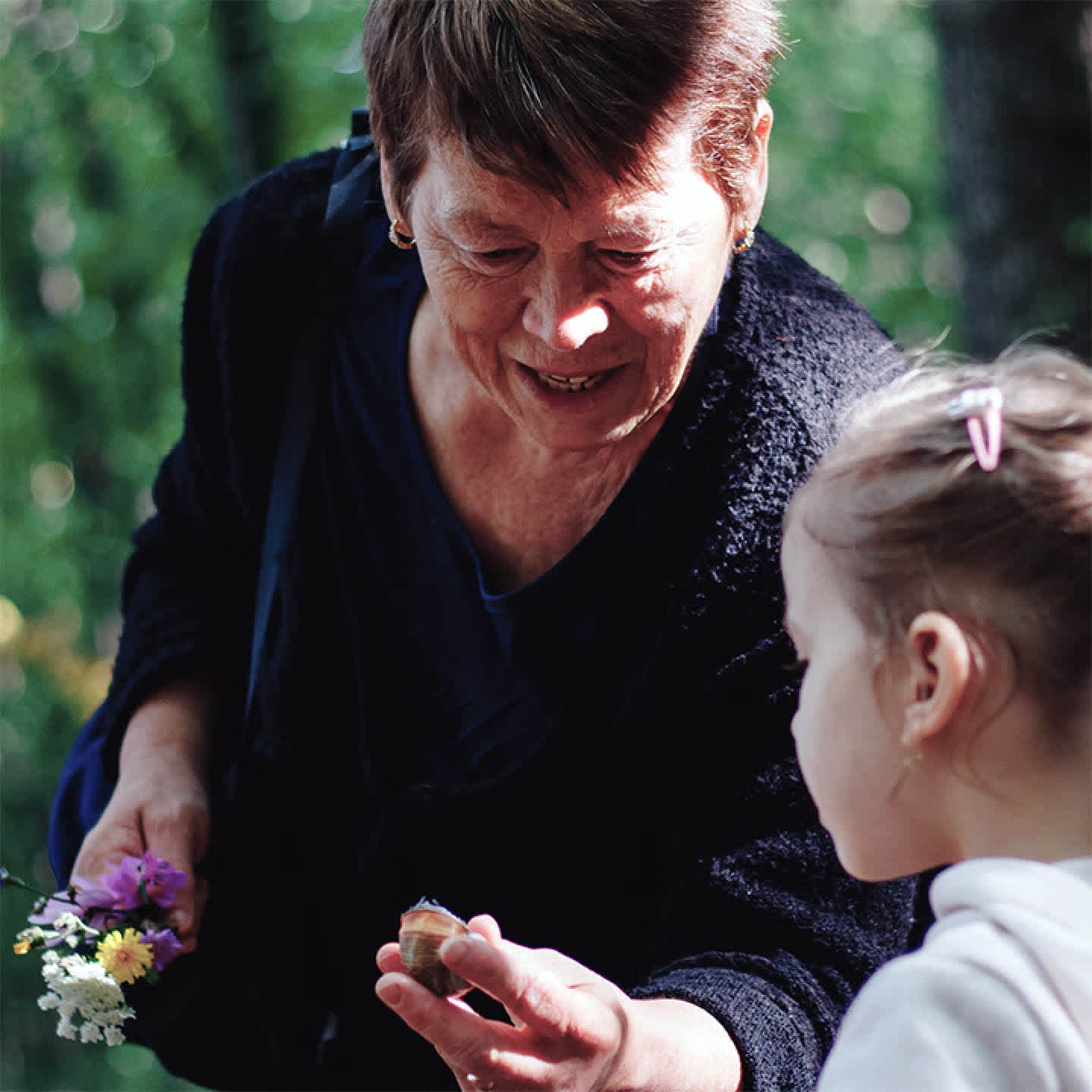 A woman and a child looking at a snail.