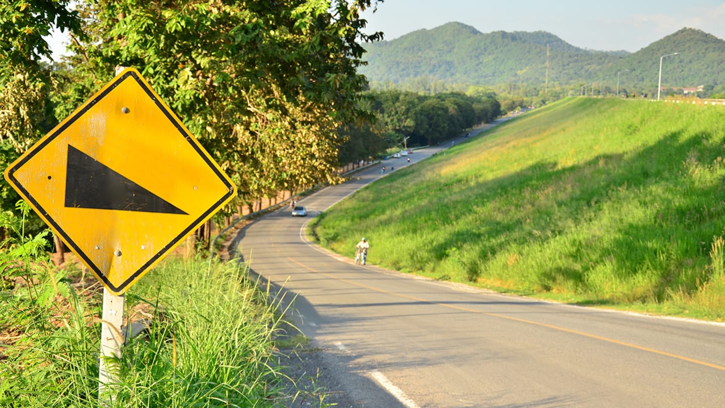 Steep incline sign by roadway.