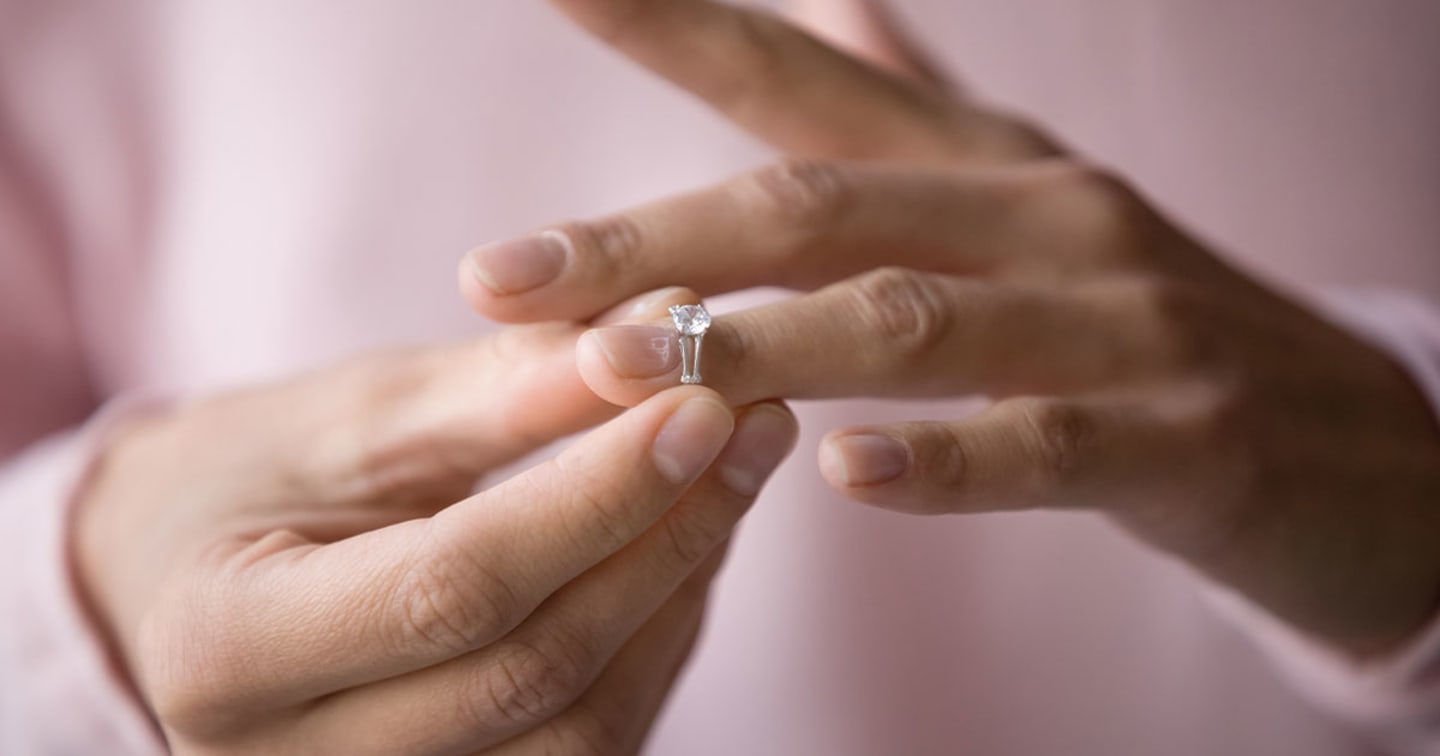 Hands removing wedding ring.