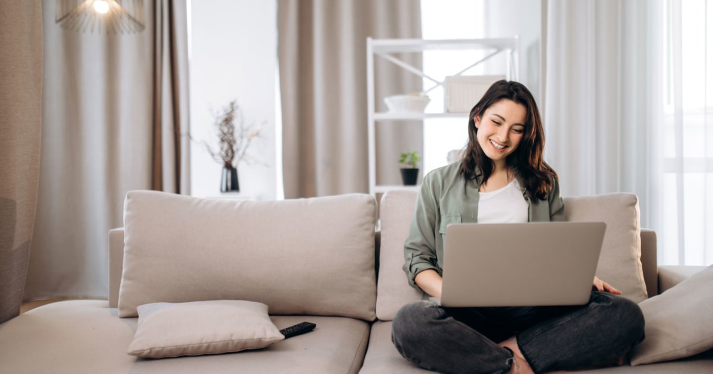 Woman with laptop sitting on couch.