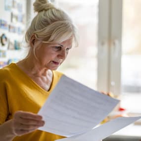 A woman reviews paperwork and considers updates to her finances.