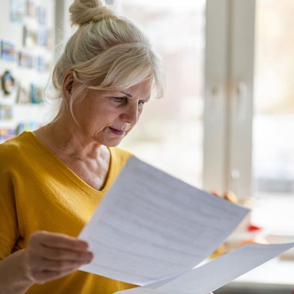 A woman reviews paperwork and considers updates to her finances.