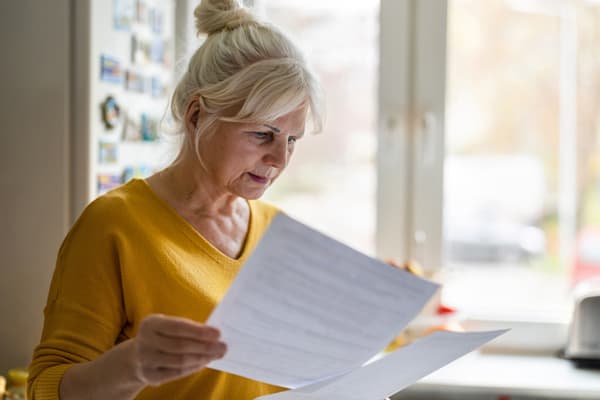 A woman reviews paperwork and considers updates to her finances.