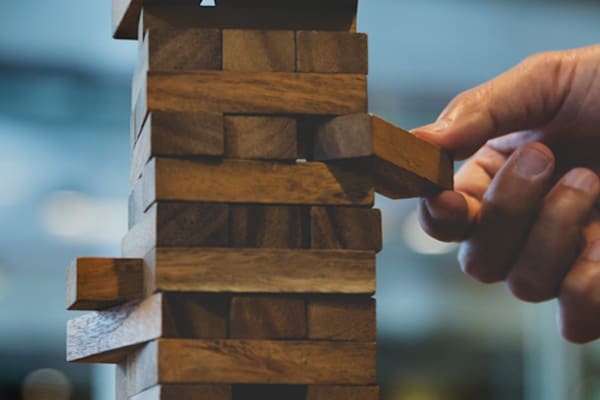Hand pulling wood piece from tumbling tower game.