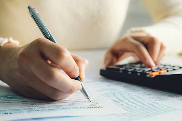 Woman at desk with tax forms and calculator.